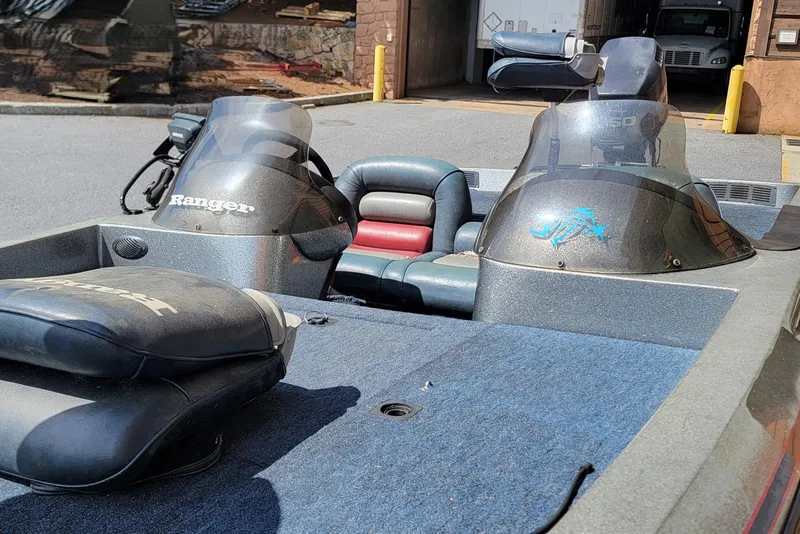 Slide: The Image of 1995 Ranger boat interior with dual consoles and cushioned seating, parked outdoors. - 11