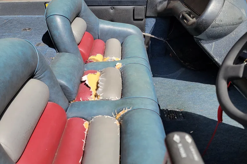 Slide: The Image of 1995 Ranger boat interior with worn, multicolored seats and visible damage. - 13
