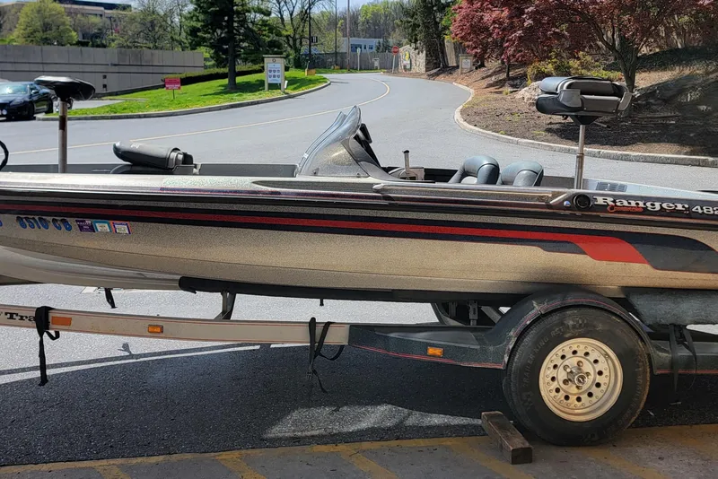 Slide: The Image of 1995 Ranger boat on trailer, parked on a sunny road with trees in the background. - 3