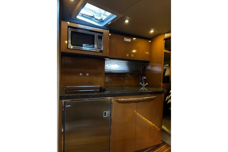 Slide: The Image of 2010 Chaparral Signature 370 yacht kitchen with microwave, fridge, and wood cabinetry. - 31