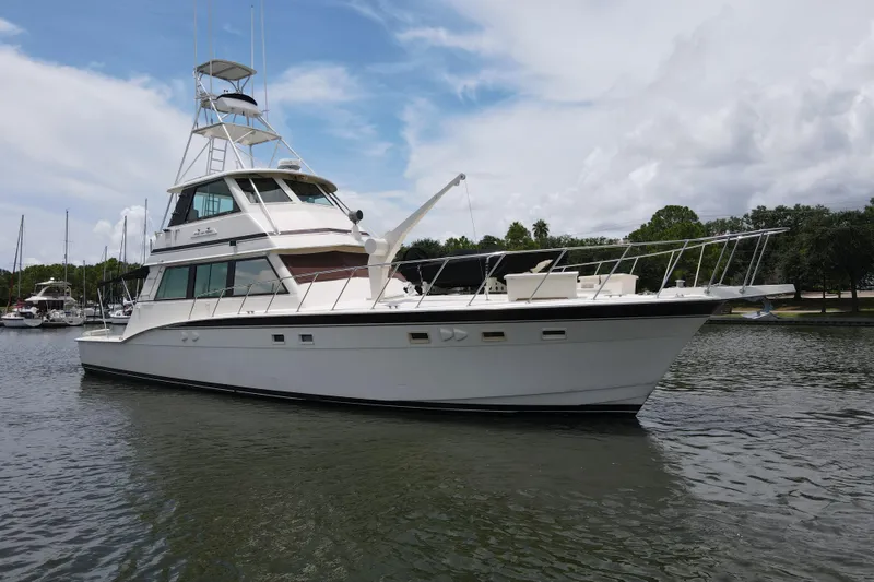 Slide: The Image of 1985 Hatteras 60 Convertible yacht on calm water, showcasing sleek design and spacious deck. - 10