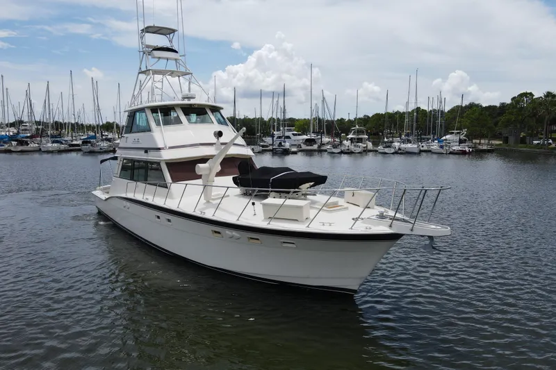 Slide: The Image of 1985 Hatteras 60 Convertible yacht docked in a marina, surrounded by sailboats. - 11