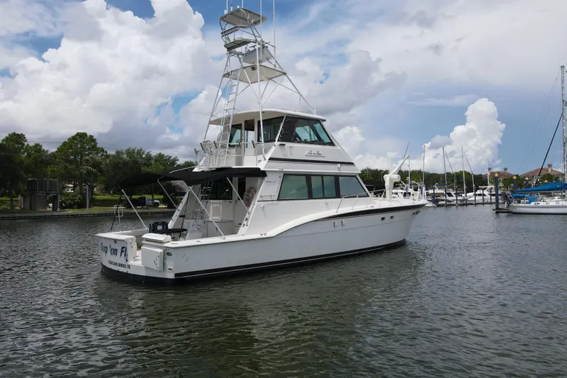 Slide: The Image of 1985 Hatteras 60 Convertible yacht docked in a marina under a cloudy sky. - 13