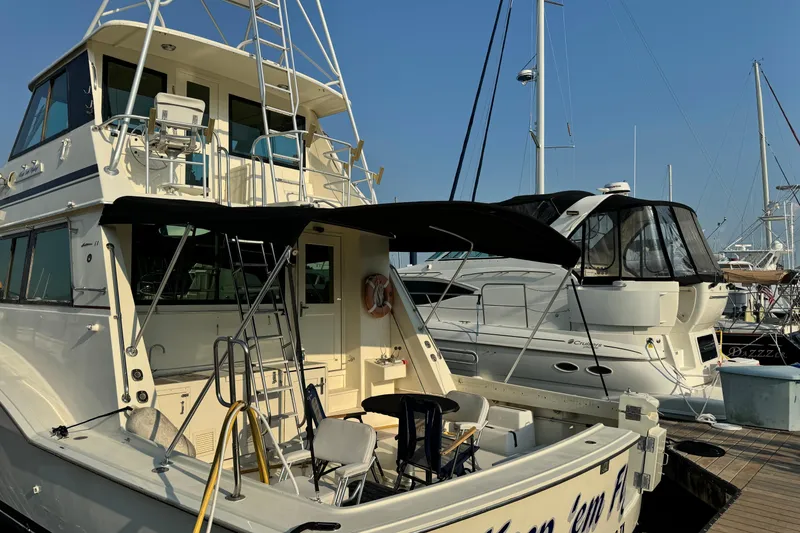 Slide: The Image of 1985 Hatteras 60 Convertible yacht docked at marina, featuring spacious deck and seating area. - 17