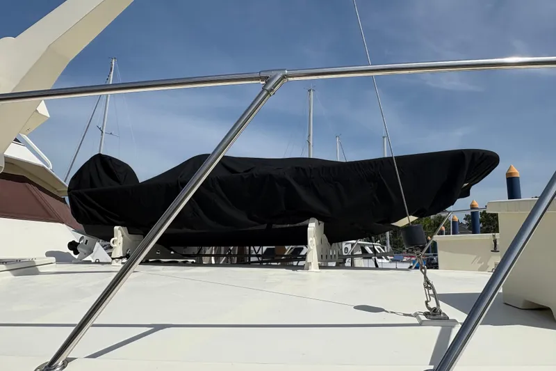 Slide: The Image of 1985 Hatteras 60 Convertible yacht deck with covered equipment, marina background. - 22