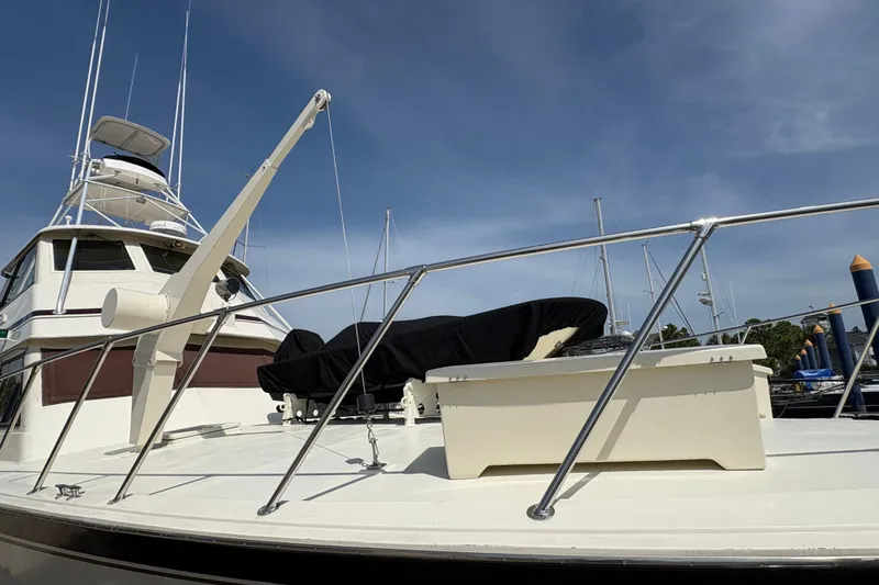 Slide: The Image of 1985 Hatteras 60 Convertible yacht with covered equipment on deck, under a clear blue sky. - 23
