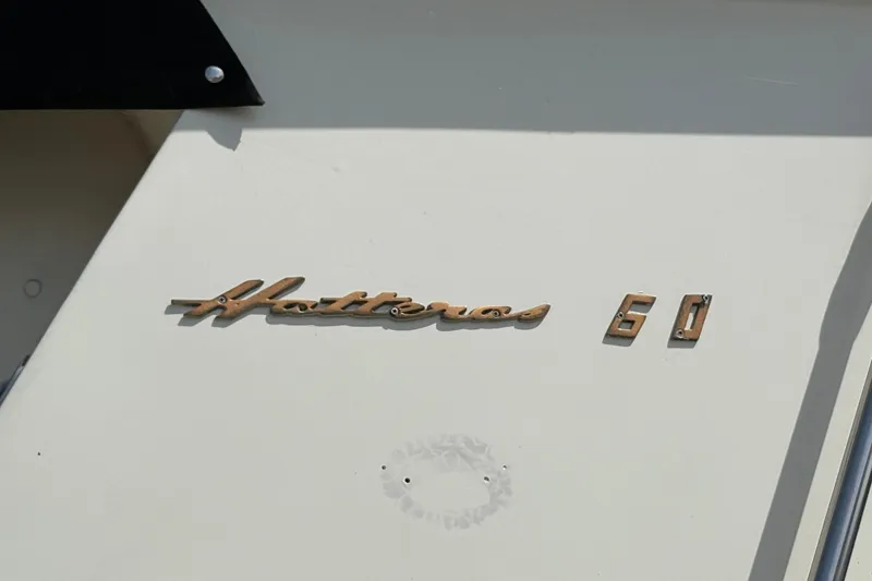 Slide: The Image of 1985 Hatteras 60 Convertible yacht emblem on a white surface. - 26
