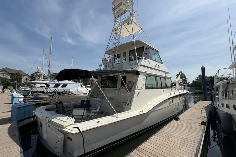 Slide: The Image of 1985 Hatteras 60 Convertible yacht docked at marina under clear sky. - 27