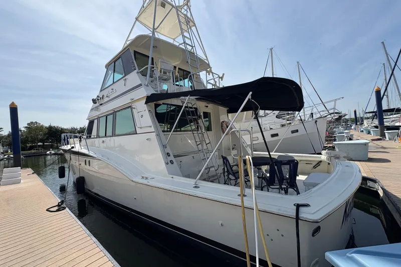 Slide: The Image of 1985 Hatteras 60 Convertible yacht docked at marina under clear sky. - 30