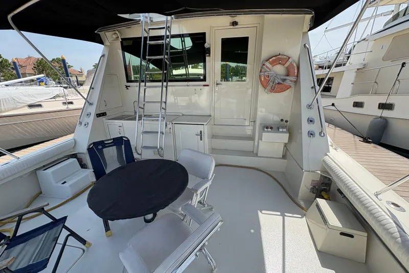 Slide: The Image of 1985 Hatteras 60 Convertible yacht deck with seating, table, and ladder. - 31
