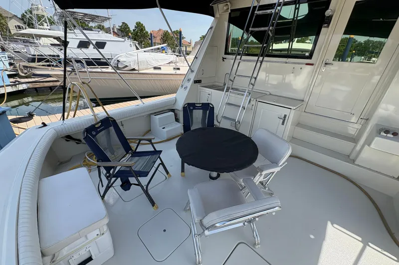 Slide: The Image of 1985 Hatteras 60 Convertible yacht deck with seating and table, docked at marina. - 32