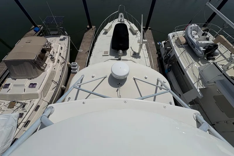 Slide: The Image of 1985 Hatteras 60 Convertible yacht docked between two boats, aerial view. - 34