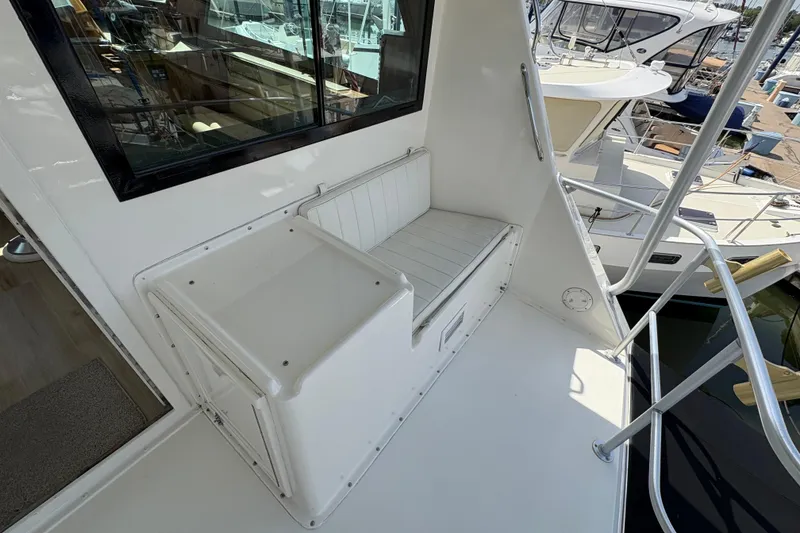 Slide: The Image of 1985 Hatteras 60 Convertible yacht deck with seating and railing, docked at marina. - 37
