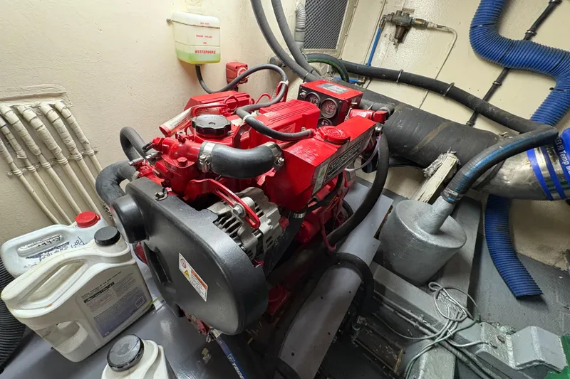Slide: The Image of Engine room of a 1985 Hatteras 60 Convertible with red machinery and maintenance supplies. - 49