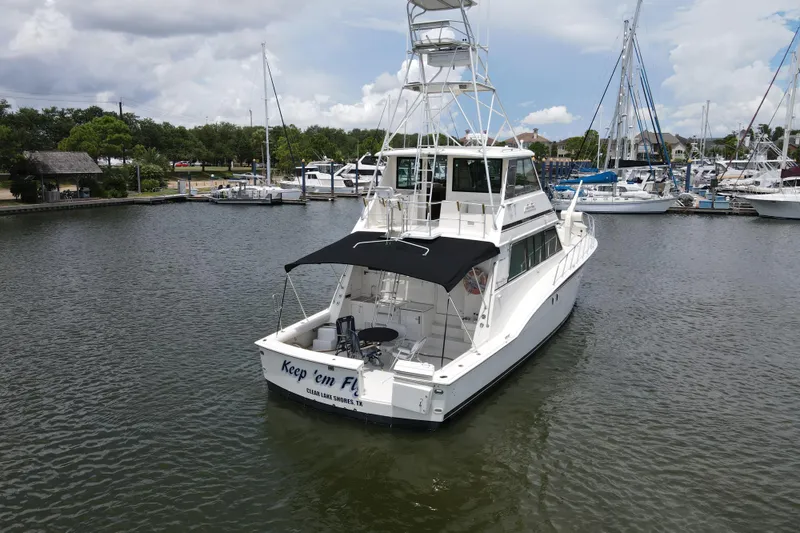 Slide: The Image of 1985 Hatteras 60 Convertible yacht docked in marina, featuring sleek design and spacious deck. - 5