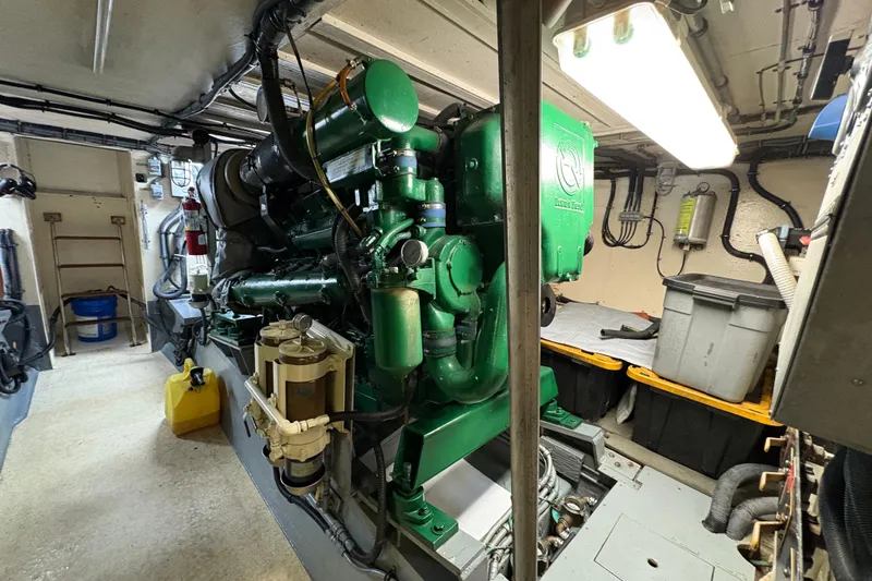 Slide: The Image of Engine room of a 1985 Hatteras 60 Convertible yacht, featuring a green marine engine. - 53