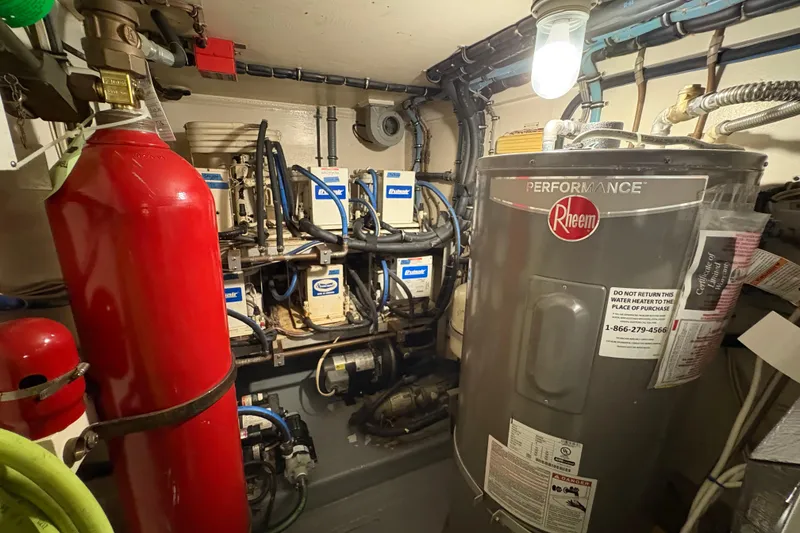 Slide: The Image of Engine room of 1985 Hatteras 60 Convertible with Rheem water heater and fire extinguisher. - 55