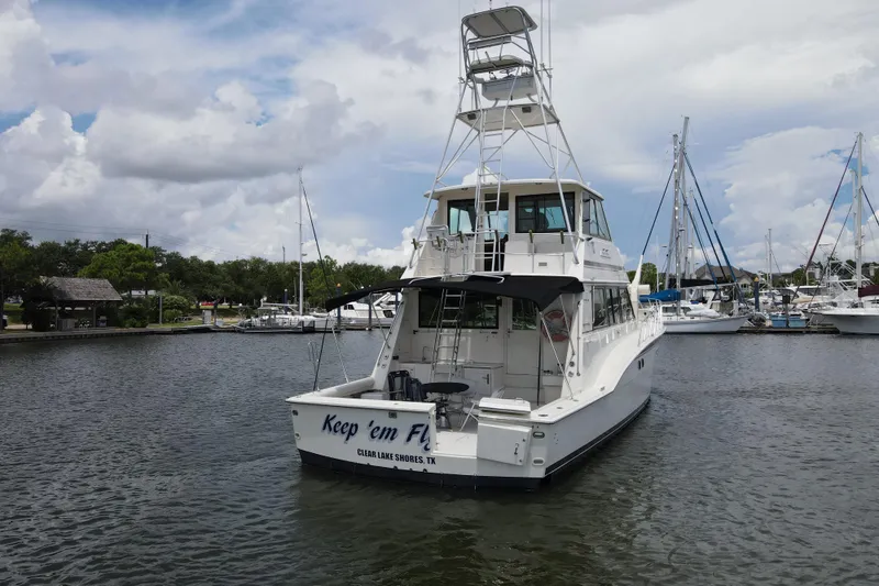 Slide: The Image of 1985 Hatteras 60 Convertible yacht docked in a marina under a cloudy sky. - 6