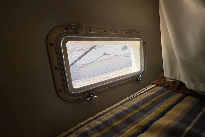 Slide: The Image of Porthole view inside 1985 Hatteras 60 Convertible yacht cabin with striped bedding. - 60