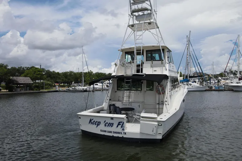 Slide: The Image of 1985 Hatteras 60 Convertible yacht docked in a marina under a cloudy sky. - 7
