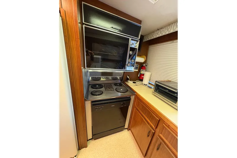 Slide: The Image of 1985 Hatteras 60 Convertible yacht kitchen with stove, oven, and wooden cabinetry. - 82