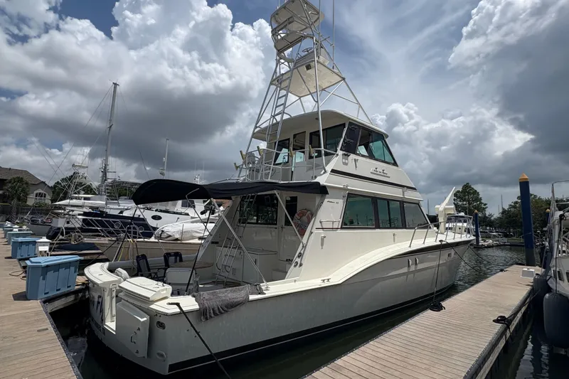 Slide: The Image of 1985 Hatteras 60 Convertible yacht docked at marina under cloudy sky. - 86
