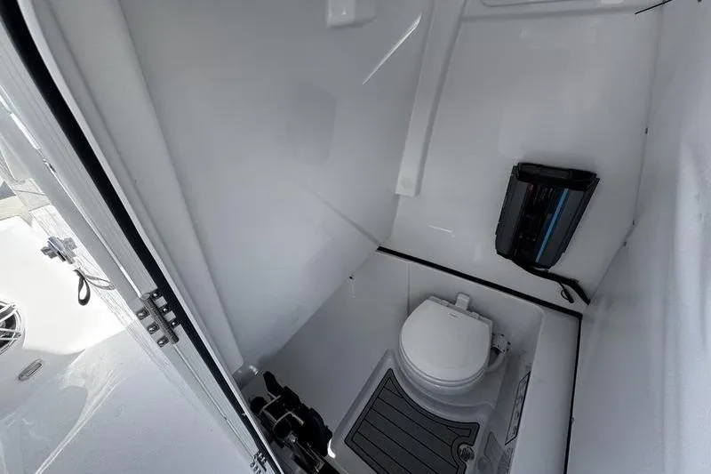 Slide: The Image of Interior of 2026 Sportsman Heritage 261 Center Console boat, featuring a compact marine toilet. - 11