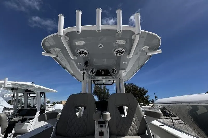 Slide: The Image of 2026 Sportsman Heritage 261 Center Console boat with T-top and rod holders under blue sky. - 21