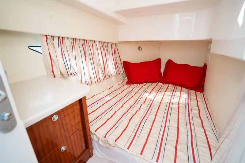 Slide: The Image of Cozy cabin interior of 2009 Intrepid 475 Sport Yacht with striped bedding and red pillows. - 12