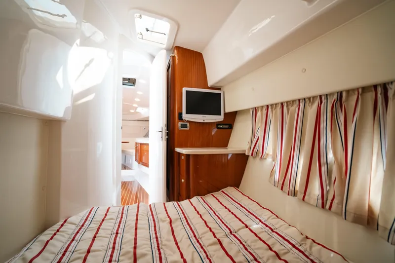 Slide: The Image of Interior cabin of 2009 Intrepid 475 Sport Yacht with striped bedding and wall-mounted TV. - 13
