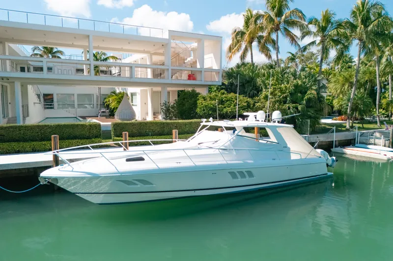 Slide: The Image of 2009 Intrepid 475 Sport Yacht docked by a modern waterfront home with palm trees. - 40