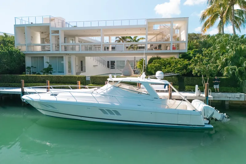 Slide: The Image of 2009 Intrepid 475 Sport Yacht docked by modern waterfront home, surrounded by lush greenery. - 41