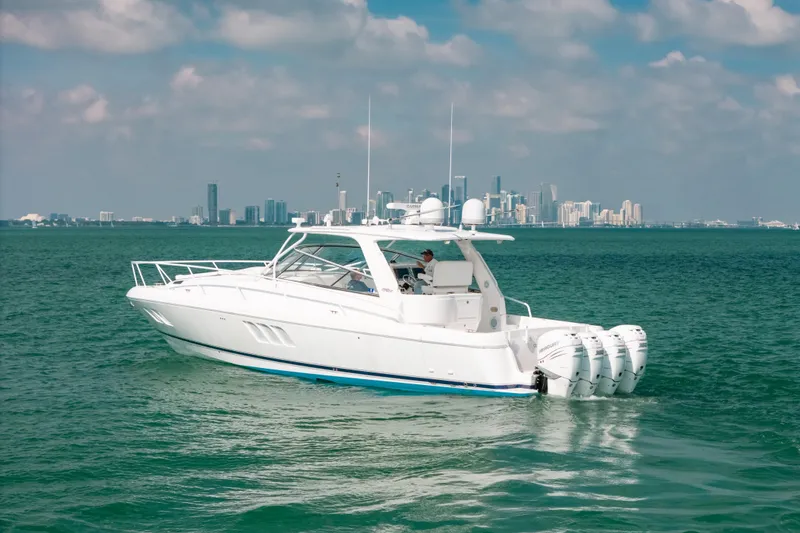 Slide: The Image of 2009 Intrepid 475 Sport Yacht cruising on turquoise waters with city skyline backdrop. - 46