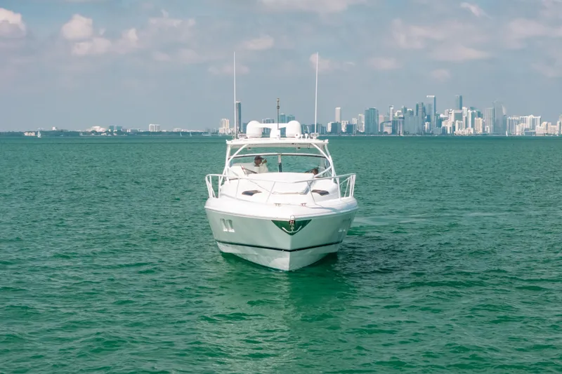 Slide: The Image of 2009 Intrepid 475 Sport Yacht cruising on turquoise waters with city skyline backdrop. - 49
