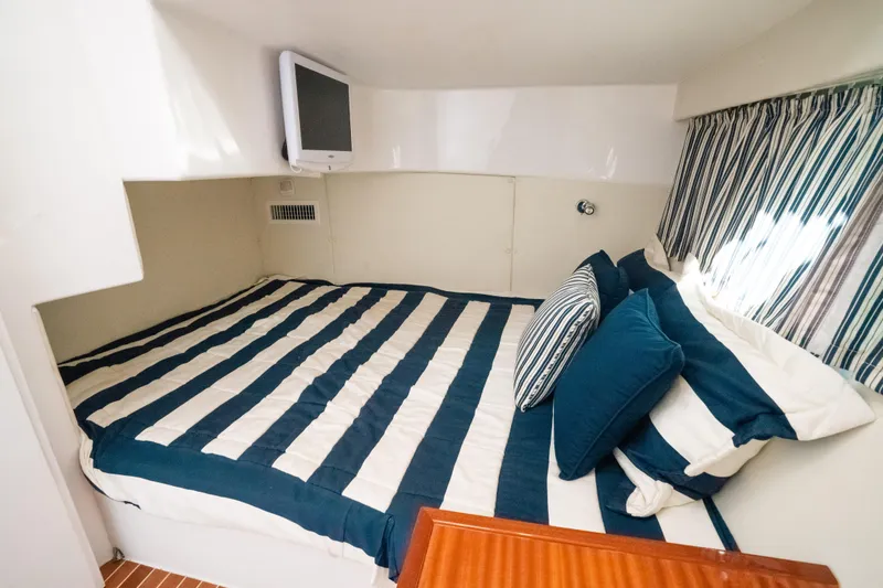 Slide: The Image of Cozy cabin interior of 2009 Intrepid 475 Sport Yacht with striped bedding and wall-mounted TV. - 6