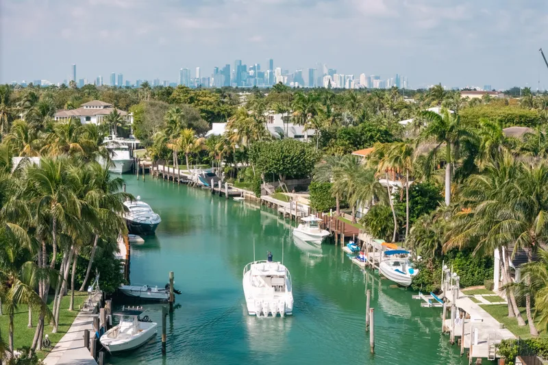 Slide: The Image of Canal view with 2009 Intrepid 475 Sport Yacht, lush greenery, and city skyline in the background. - 72