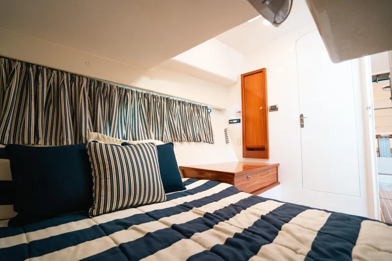 Slide: The Image of Luxurious cabin interior of 2009 Intrepid 475 Sport Yacht with striped bedding and wooden accents. - 9