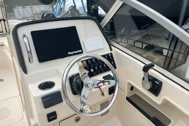 Slide: The Image of 2018 Grady-White Freedom 235 boat dashboard with steering wheel and Raymarine display. - 27