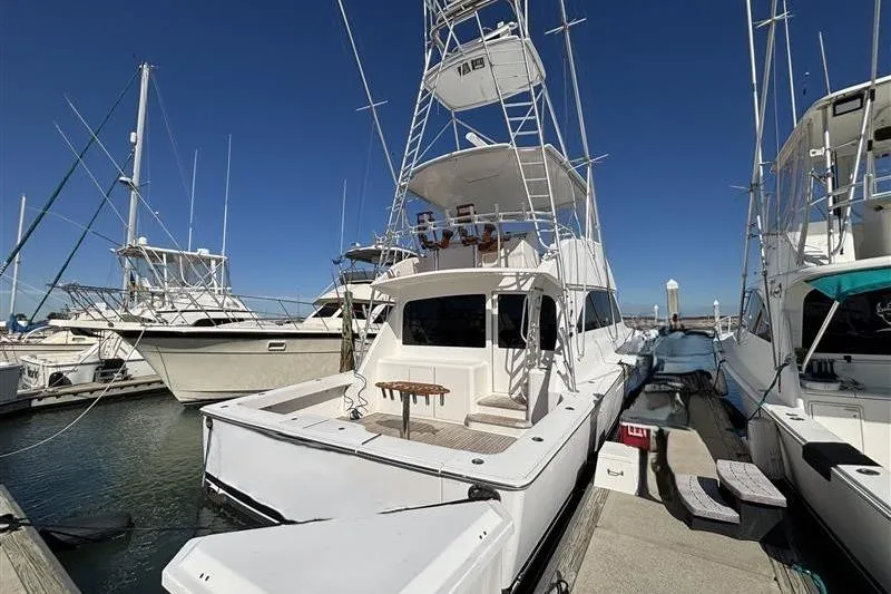 Slide: The Image of 2007 Viking 52 Convertible yacht docked at marina under clear blue sky. - 2