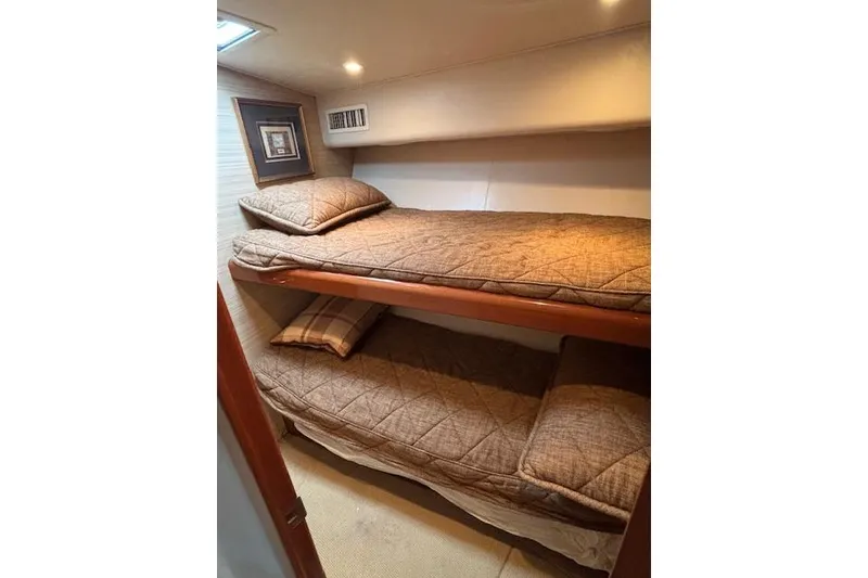 Slide: The Image of Bunk beds in 2007 Viking 52 Convertible yacht cabin, featuring cozy bedding and warm lighting. - 27