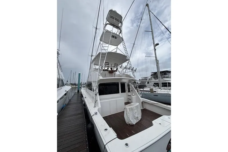Slide: The Image of 2007 Viking 52 Convertible yacht docked, showcasing spacious deck and tower under cloudy skies. - 4