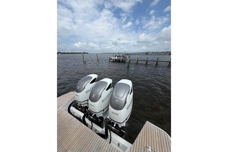 Slide: The Image of Triple Suzuki outboard engines on a 2022 Schaefer 400 Sport boat, docked by the water. - 14