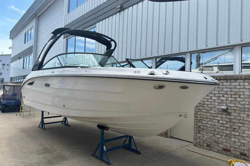 The Image of 2026 Sea Ray SDX 250 boat displayed on stands outside a building. - 0