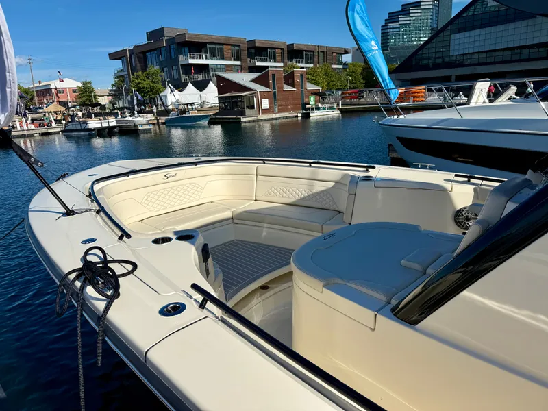 Slide: The Image of A 2027 Scout 330 LXF docked in a marina. The boat features a spacious bow area with seating. - 15