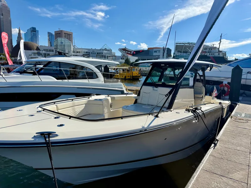 Slide: The Image of A 2027 Scout 330 LXF docked at a modern marina with city buildings in the background. - 13