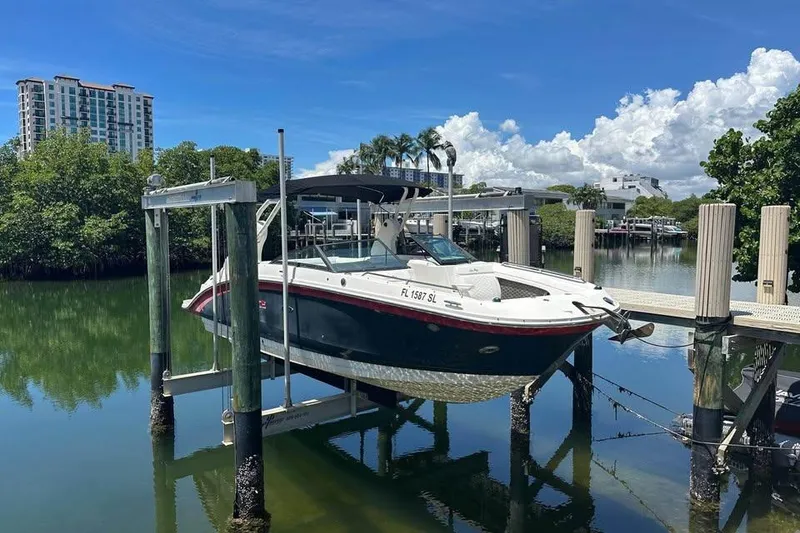 The Image of 2019 Sea Ray SDX 270 Outboard boat docked on lift, scenic waterfront view. - 0