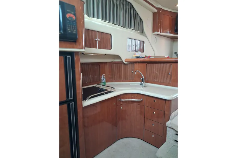 Slide: The Image of 2003 Sea Ray 400 Sedan Bridge kitchen with wood cabinetry and modern appliances. - 21