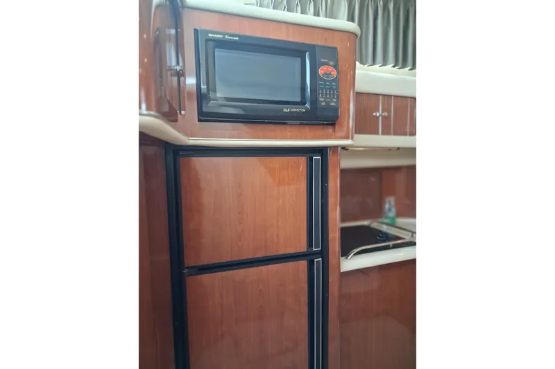 Slide: The Image of 2003 Sea Ray 400 Sedan Bridge kitchen with microwave and wooden cabinetry. - 33
