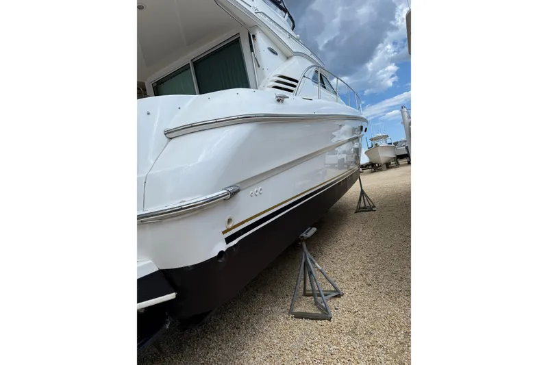 Slide: The Image of 2003 Sea Ray 400 Sedan Bridge yacht on stands, side view under cloudy sky. - 4