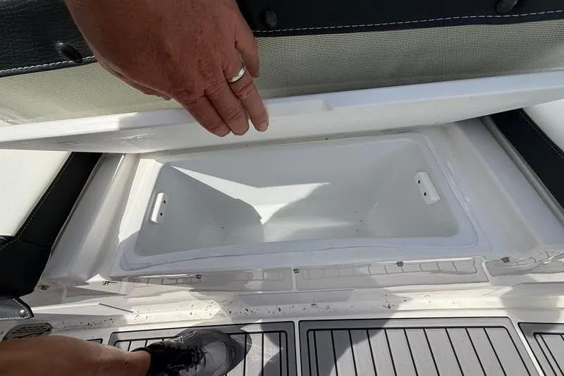 Slide: The Image of Storage compartment on a 2022 Tidewater 272 LXF boat, with hand lifting the lid. - 11